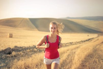 A woman jogging through vast, golden wheat fields under the summer sun, symbolizing freedom and adventure.