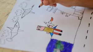 Close-up of a child drawing spaceships and astronauts. Creative art expression in a playful setting.