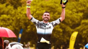 Smiling athlete raises arms in victory at outdoor marathon finish line.